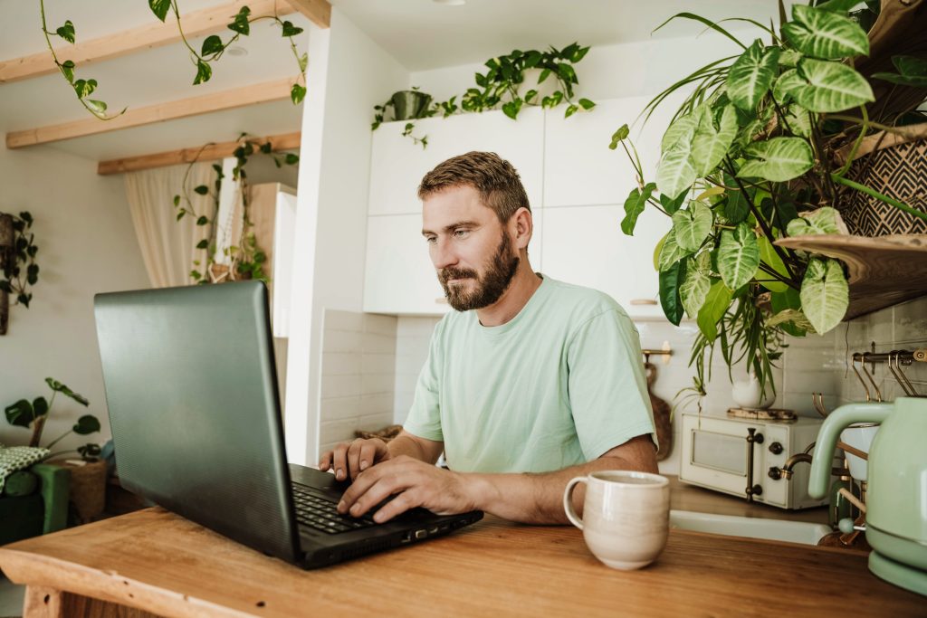 Mann benutzt Laptop in der Küche zu Hause